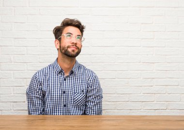 Ararken, bir şey eğlenceli düşünme ve bir fikir, hayal gücü, mutlu ve heyecanlı kavramı olan oturan genç beyaz adam