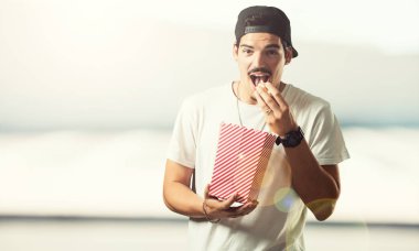 Genç rapçi adam mutlu ve hayran, bir çizgili patlamış mısır kova tutarak yeni film, gözleri açık ve hayranlık ifade tarafından şaşırttı