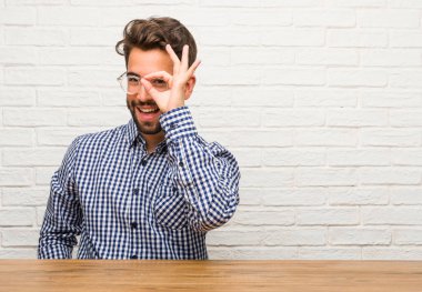 Genç beyaz adam neşeli ve kendine güvenen ok jest yapıyor