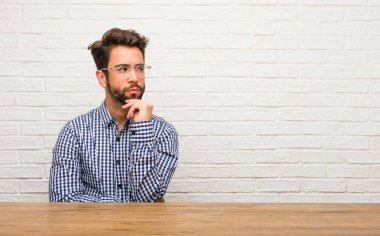 Şüphe ve karışık, düşünme, bir fikir ya da bir şey hakkında endişeli oturan genç beyaz adam