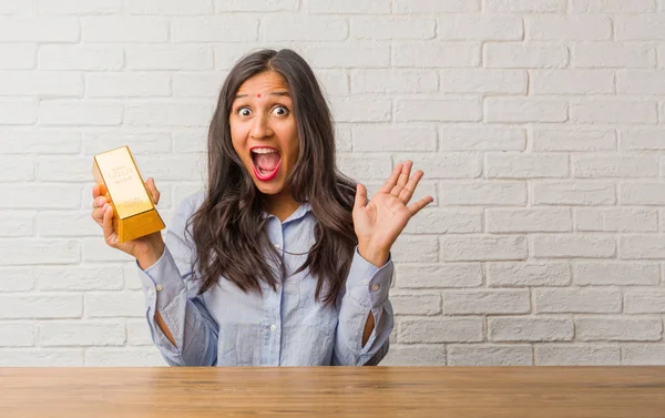 Young indian woman screaming happy, surprised by an offer or a promotion, gaping, jumping and proud