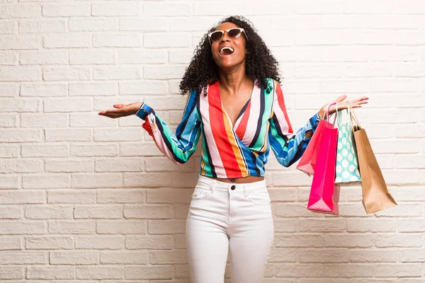 笑いやレンガの壁に楽しいショッピング バッグで若い黒人女性 — ストック写真