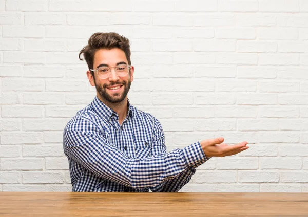 Joven Caucásico Sentado Sosteniendo Algo Con Las Manos Mostrando Producto —  Fotos de Stock