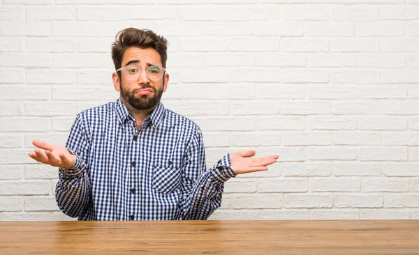 Kaukasische Jongeman Zitten Twijfelen Schouderophalend Schouders Concept Van Besluiteloosheid Onveiligheid — Stockfoto