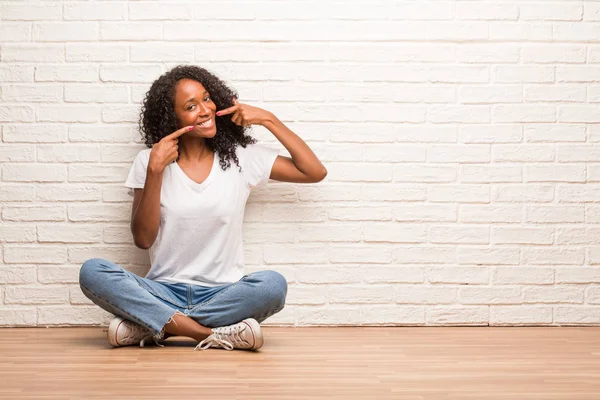 Joven Mujer Negra Sentada Suelo Madera Sonríe Señalando Boca Contra —  Fotos de Stock