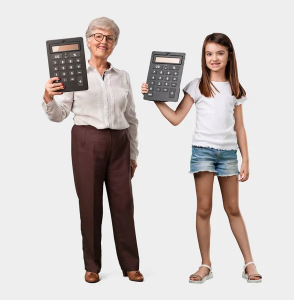 整个身体的老太太和她的孙女开朗和微笑 持有计算器 做精确的计算 数据信息 — 图库照片