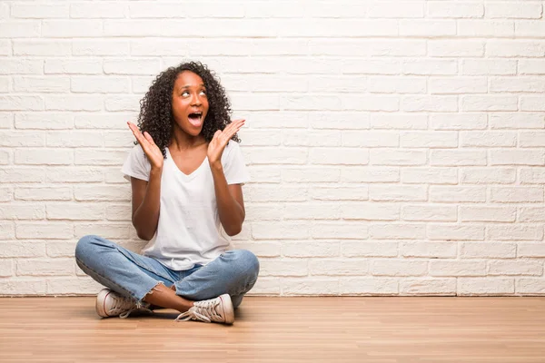 Young Black Woman Sitting Wooden Floor Surprised Shocked Brick Wall — Stock Photo, Image