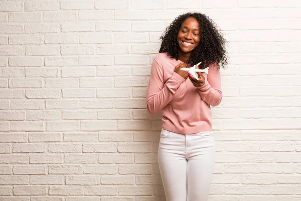 年轻的黑人妇女与飞机模型非常高兴和兴奋 对砖墙微笑 — 图库照片