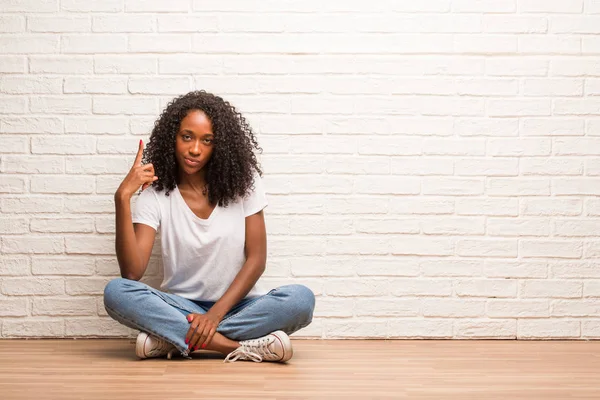 Νεαρή Μαύρη Γυναίκα Που Κάθεται Ένα Ξύλινο Πάτωμα Που Δείχνει — Φωτογραφία Αρχείου