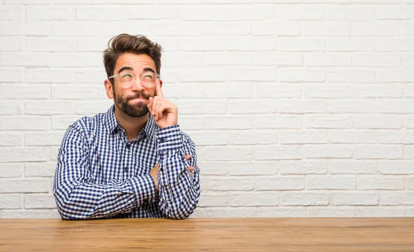 Unga Kaukasiska Man Sittande Tänka Och Titta Upp Förvirrad Över — Stockfoto