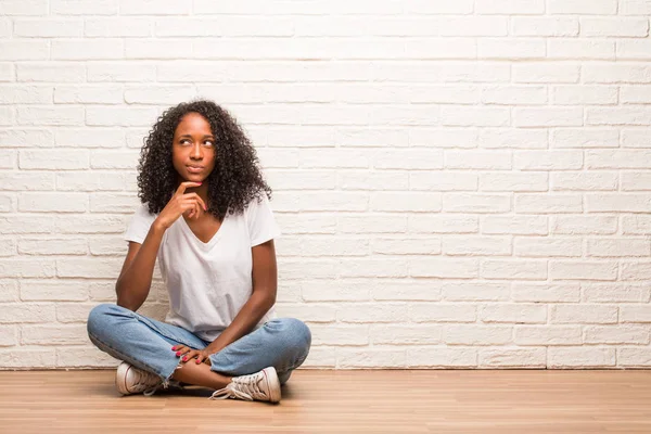 Νεαρή Μαύρη Γυναίκα Που Κάθεται Στο Ξύλινο Πάτωμα Σκέφτεται Και — Φωτογραφία Αρχείου