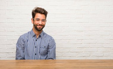 Neşeli ve büyük bir gülümseme ile kendinden emin, samimi ve içten, oturan genç beyaz adam pozitifliği ve başarı ifade etmek