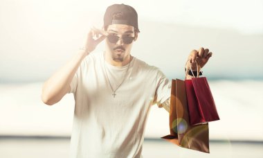 Genç rapçi neşeli adam ve gülümseyen, alışveriş çantaları taşırken çok heyecanlı alışveriş git ve yeni tekliflere bak hazır