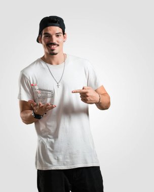 Genç rapçi dostum gülümseyen ve mutlu, holding alışveriş sepeti bir minyatür kavramı alışveriş, tüketim ve Noel, internet alışveriş ve Ticaret için kullanılabilir