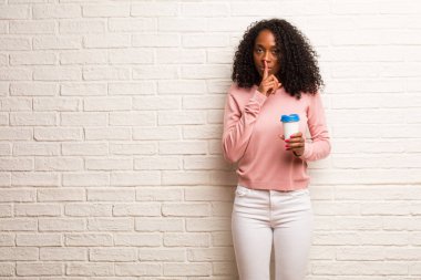 Duvara karşı sessizlik isteyen tek kullanımlık kahve fincanı olan siyah kadın