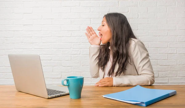 Young indian woman at the office whispering gossip undertone, trying not to be heard, is warning of a possible weakness or an opportunity