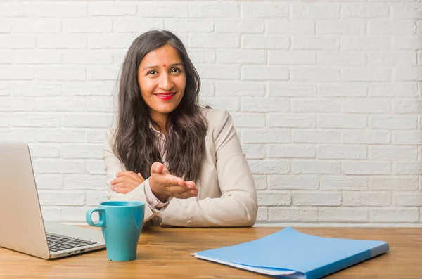 Young indian woman at office reaching out to greet someone