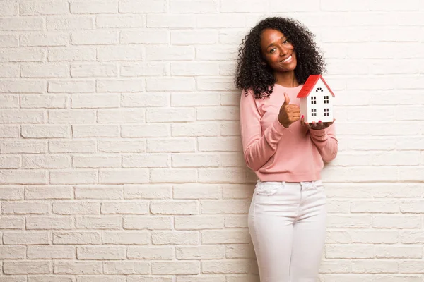 Young black woman cheerful and excited, smiling and raising her thumb up, concept of success and approval, ok gesture