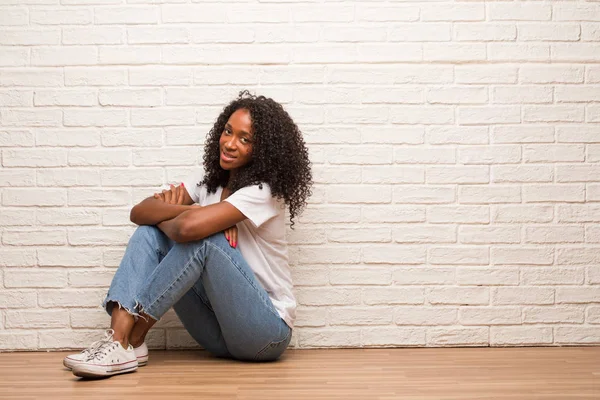 Jonge Zwarte Vrouw Zitten Een Houten Vloer Met Gekruiste Armen — Stockfoto