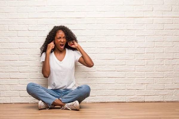 Young Black Woman Sitting Wooden Floor Covering Ears Hands Brick — Stock Photo, Image