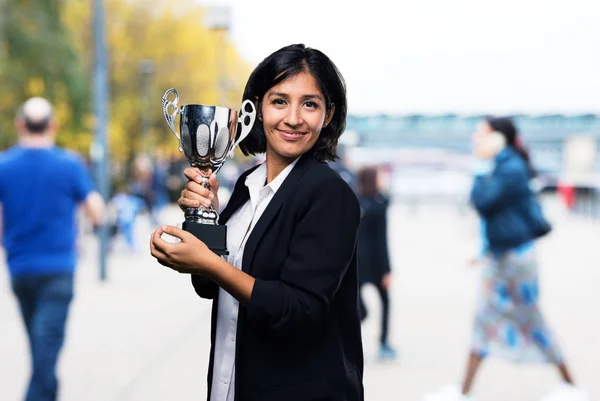 latin business woman holding a trophy
