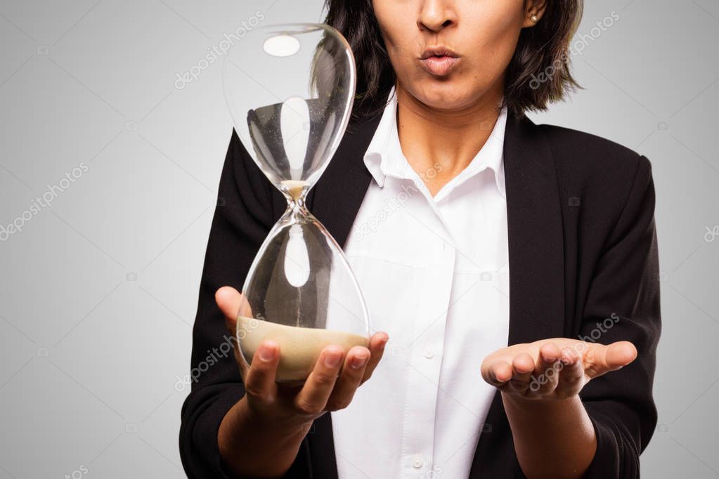 latin business woman holding a sand timer