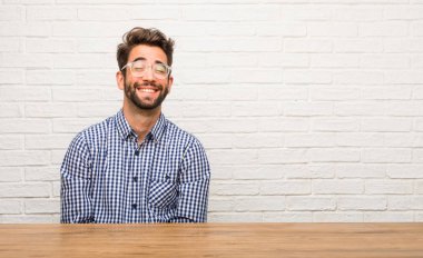 Neşeli ve büyük bir gülümseme ile kendinden emin, samimi ve içten, oturan genç beyaz adam pozitifliği ve başarı ifade etmek