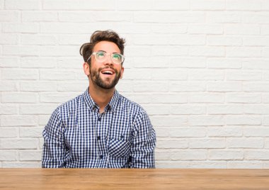 Ararken, bir şey eğlenceli düşünme ve bir fikir, hayal gücü, mutlu ve heyecanlı kavramı olan oturan genç beyaz adam