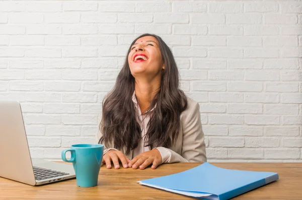 Young indian woman at the office laughing and having fun, being relaxed and cheerful, feels confident and successful