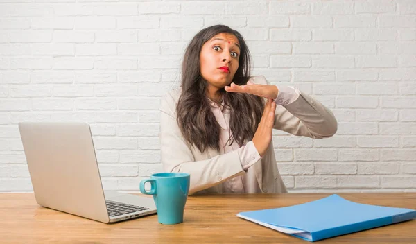 Young indian woman at office tired and bored, making timeout gesture, needs to stop because of work stress, time concept