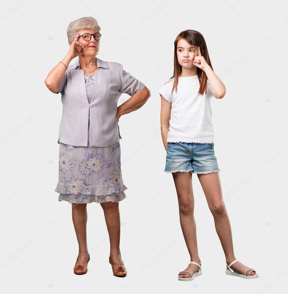Full body of an elderly lady and her granddaughter thinking and looking up, confused about an idea, would be trying to find a solution