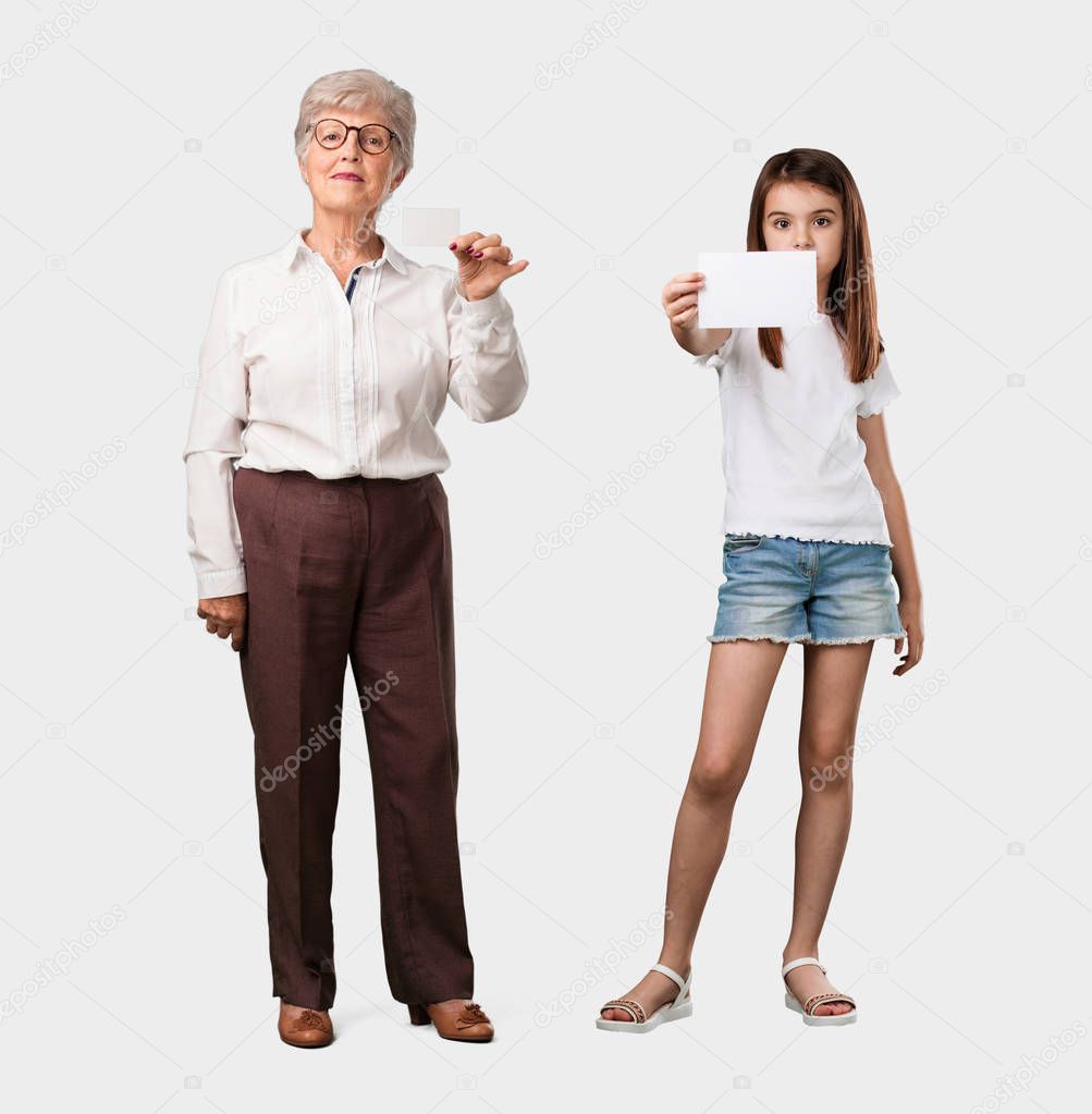Full body of an elderly lady and her granddaughter smiling confident, offering a business card, has a thriving business, copy space to write whatever you want