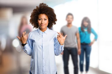 Genç siyah kadının arka plan bulanık insanlar ile iyi şanslar jest yapması