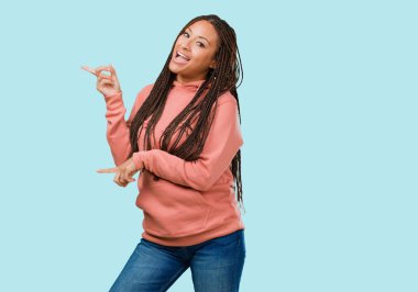 Tarafına işaret örgü giyen genç bir siyah kadın portresi, gülümseyen bir şey, doğal ve rahat sunan şaşırttı