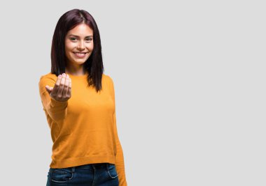 Genç ve güzel bir kadın, kendinden emin ve gülümsüyor. Elleriyle jest yapıyor. Olumlu ve arkadaş canlısı.