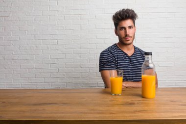 Kendinden emin ve göstermek güç hissi ve heybetli, kollarını, ciddi geçiş bir masada oturan genç yakışıklı ve doğal adam. Bir kahvaltı yapıyor, portakal suyu ve tahıl bowl içerir.