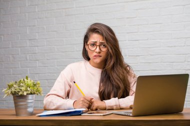 Boğulmuş ve endişeli masada oturan genç öğrenci latin kadın portresi