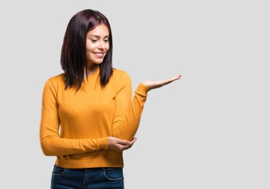 Elleriyle bir şey tutan, bir ürün, gülümseyen ve neşeli gösterilen, hayali bir nesne sunan kadın genç güzel