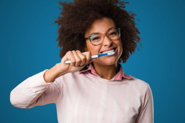 siyah kadın mavi arka plan üzerinde diş fırçası kullanarak