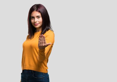 Genç ve güzel bir kadın, kendinden emin ve gülümsüyor. Elleriyle jest yapıyor. Olumlu ve arkadaş canlısı.