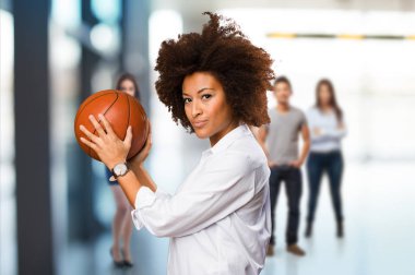 bulanık insanlarla bir sepet topu arka planda tutan genç siyah kadın