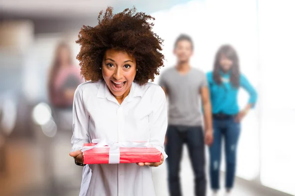 young black woman holding a gift with blurred people in background