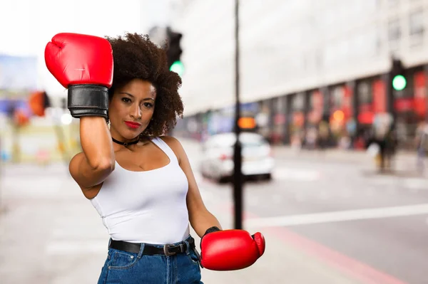 young black woman using boxing gloves on blurred background