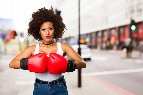 young black woman using boxing gloves on blurred background