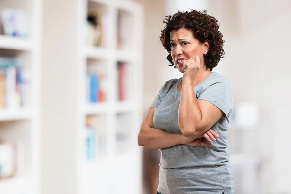 Middle aged woman biting nails, nervous and very anxious and scared for the future, feels panic and stress