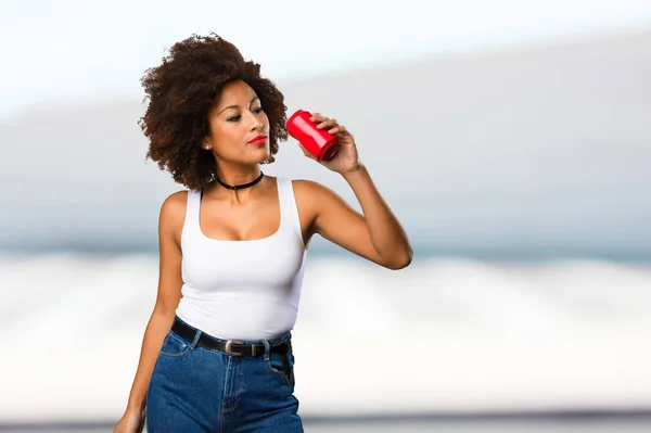 young black woman holding soda can on blurred background
