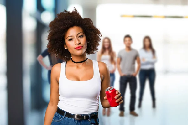 young black woman holding soda drink with blurred people in background