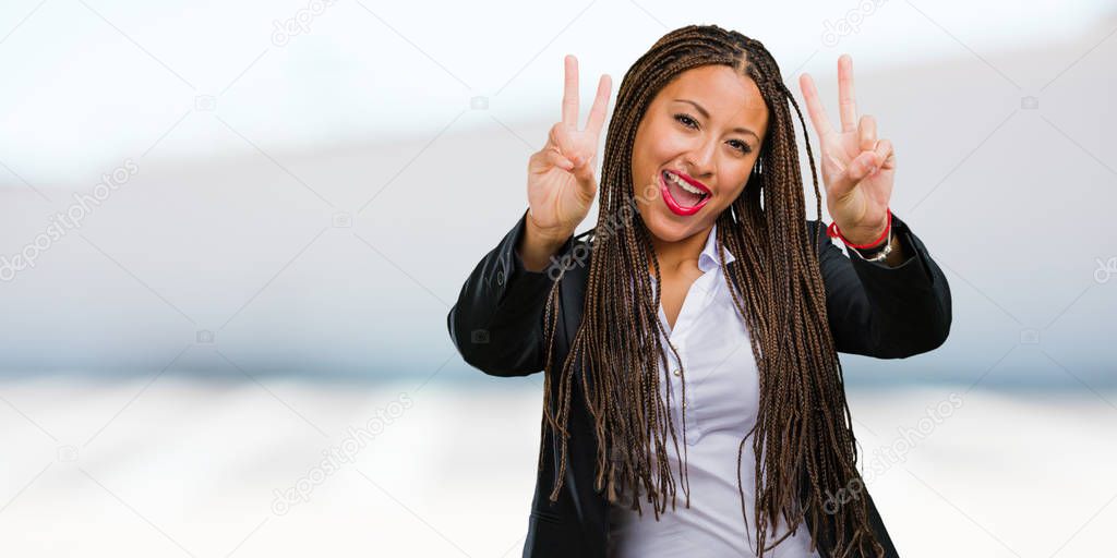 Portrait of a young black business woman fun and happy, positive and natural, makes a gesture of victory, peace concept