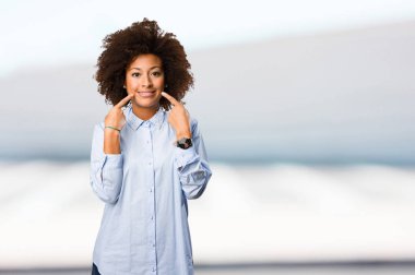 Genç siyah kadın ağzını bulanık arka plan üzerine işaret