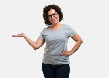 Elleriyle bir şey tutan, bir ürün, gülümseyen ve neşeli gösterilen, hayali bir nesne sunan kadın orta yaşlı